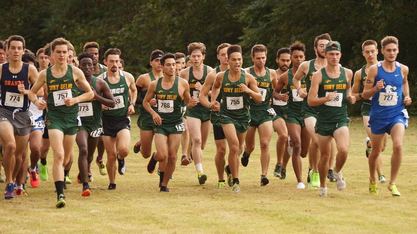 The men's cross country team runs out of the starting line in a pack.