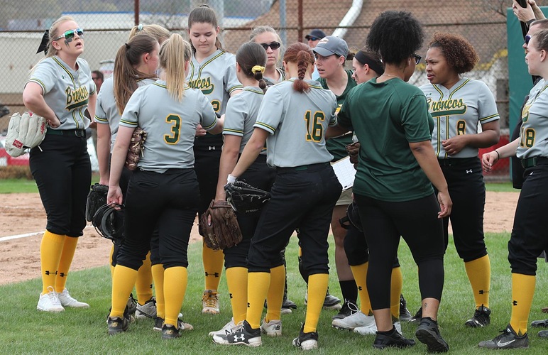 The softball team meeting together between innings of a game. 