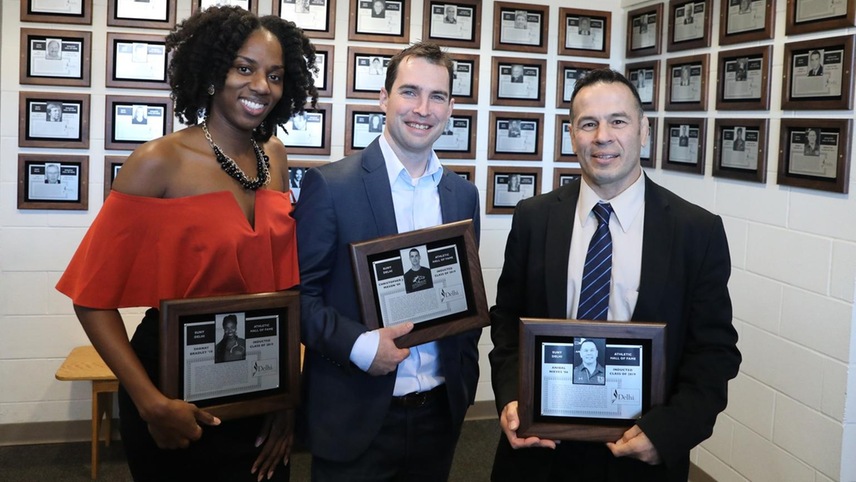 Shanay Bradley, Chris Mason, and Anibal Nieves stand in front of the Hall of Fame with their plaques.