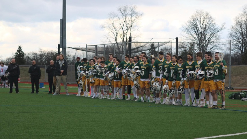 The SUNY Delhi men's lacrosse team stands on the sideline during the national anthem.