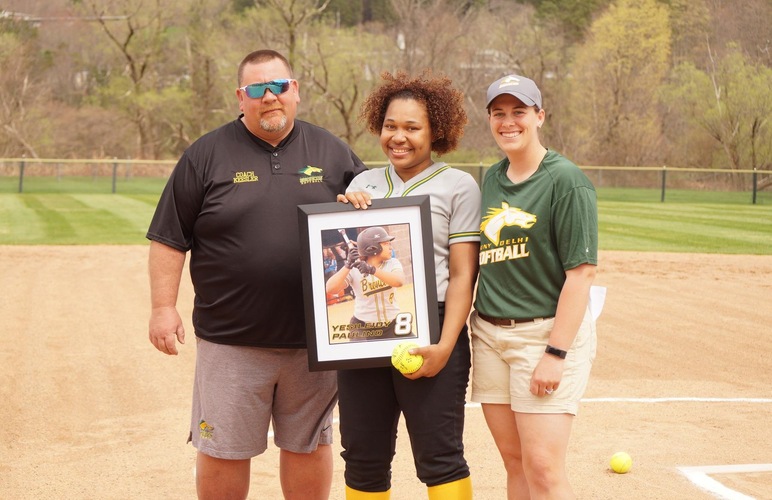 Graduating player Yesileidy Paulino receiving her framed photo with coaches Meagan Hillard and Greg Keesler on grad day. 