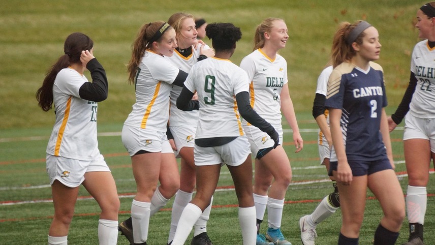The women's soccer team celebrates after a goal, with Olivia Curry putting her arms around goal-scorer Alexa DuBois.