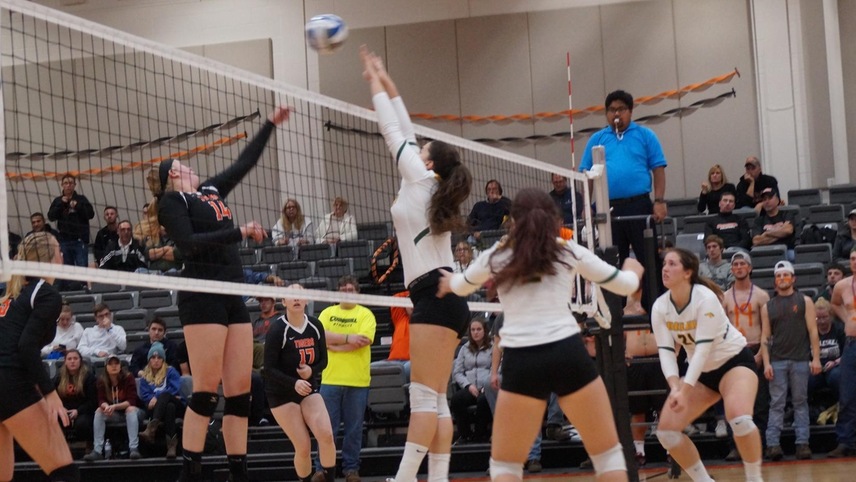 Haylee Lefebvre going up for a block with her teammates behind her looking on.