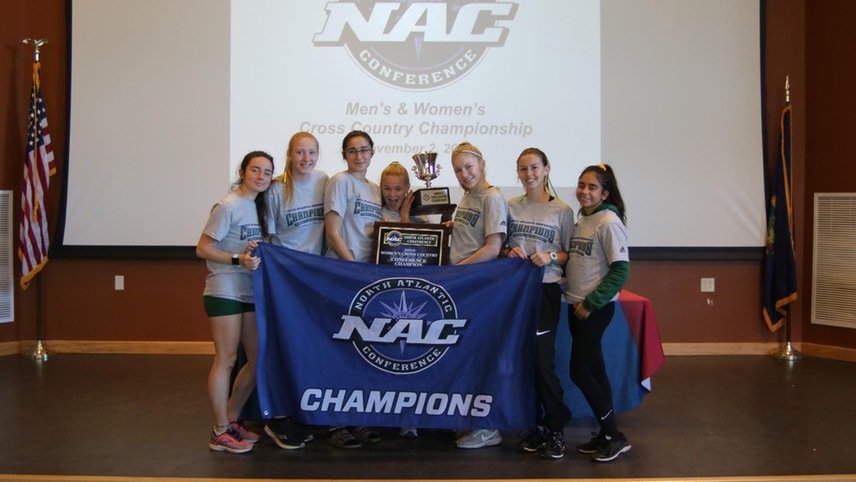 The women's cross country team in their NAC championship shirts holding their NAC team title.