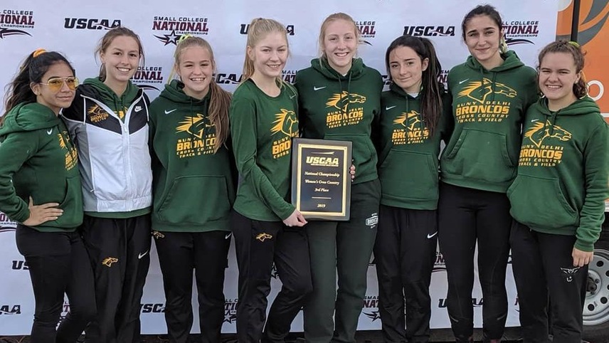 The women's cross country team holds their third place USCAA National Championship plaque.